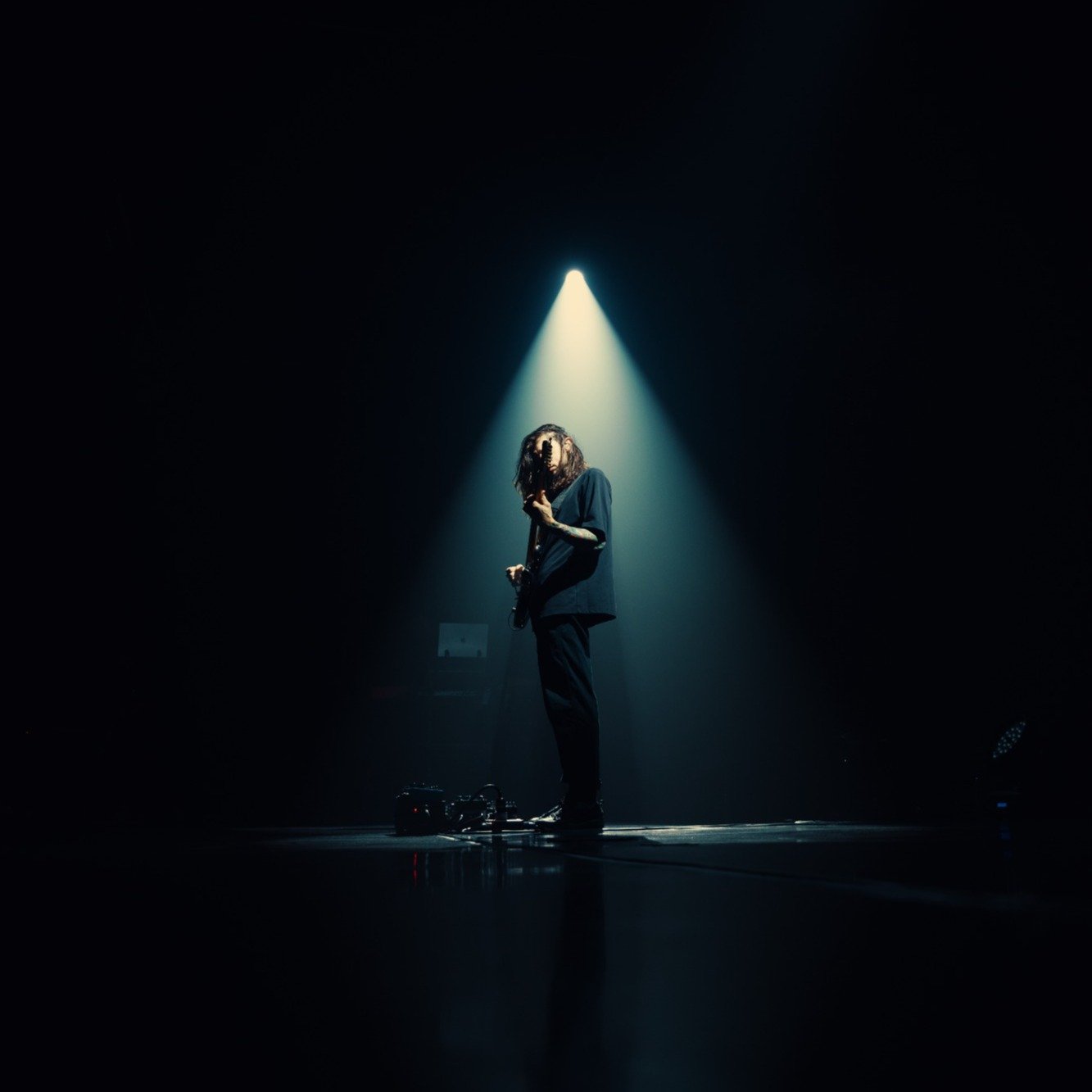Séfer Dillan tocando guitarra sob um foco de luz no palco